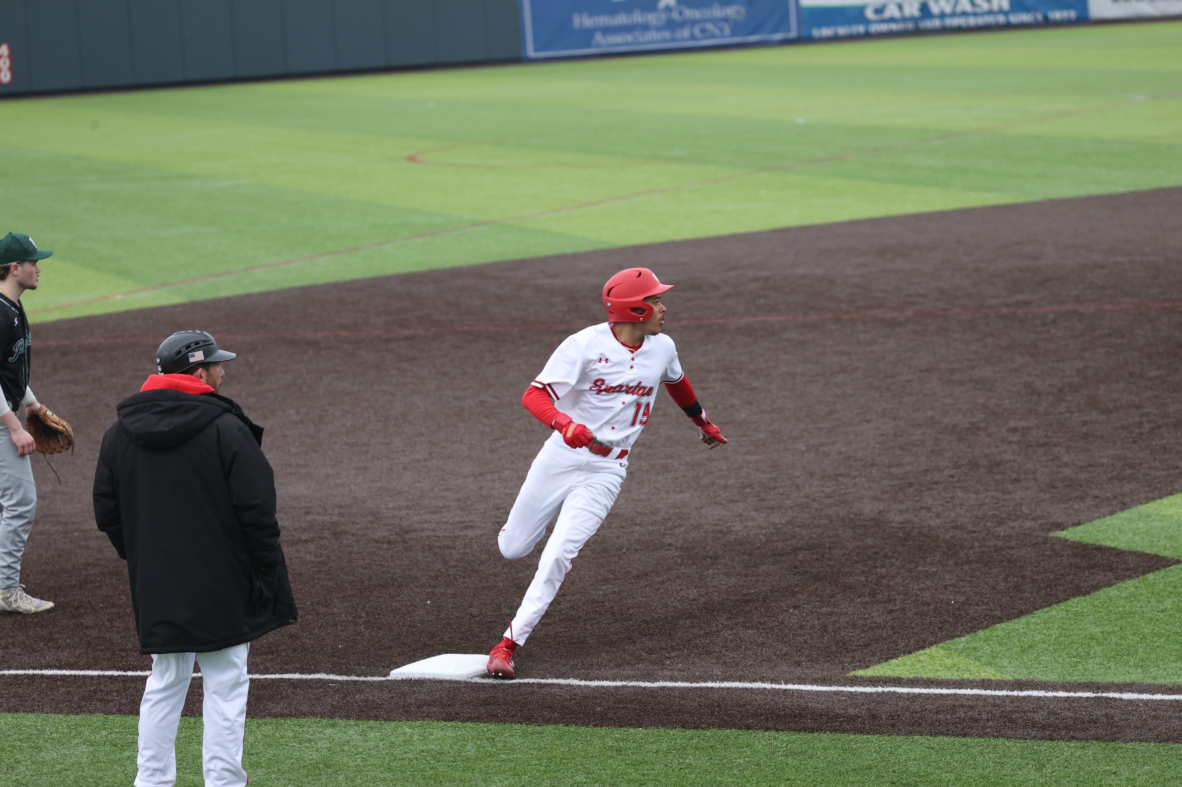 A Cayuga baseball player rounds third base.