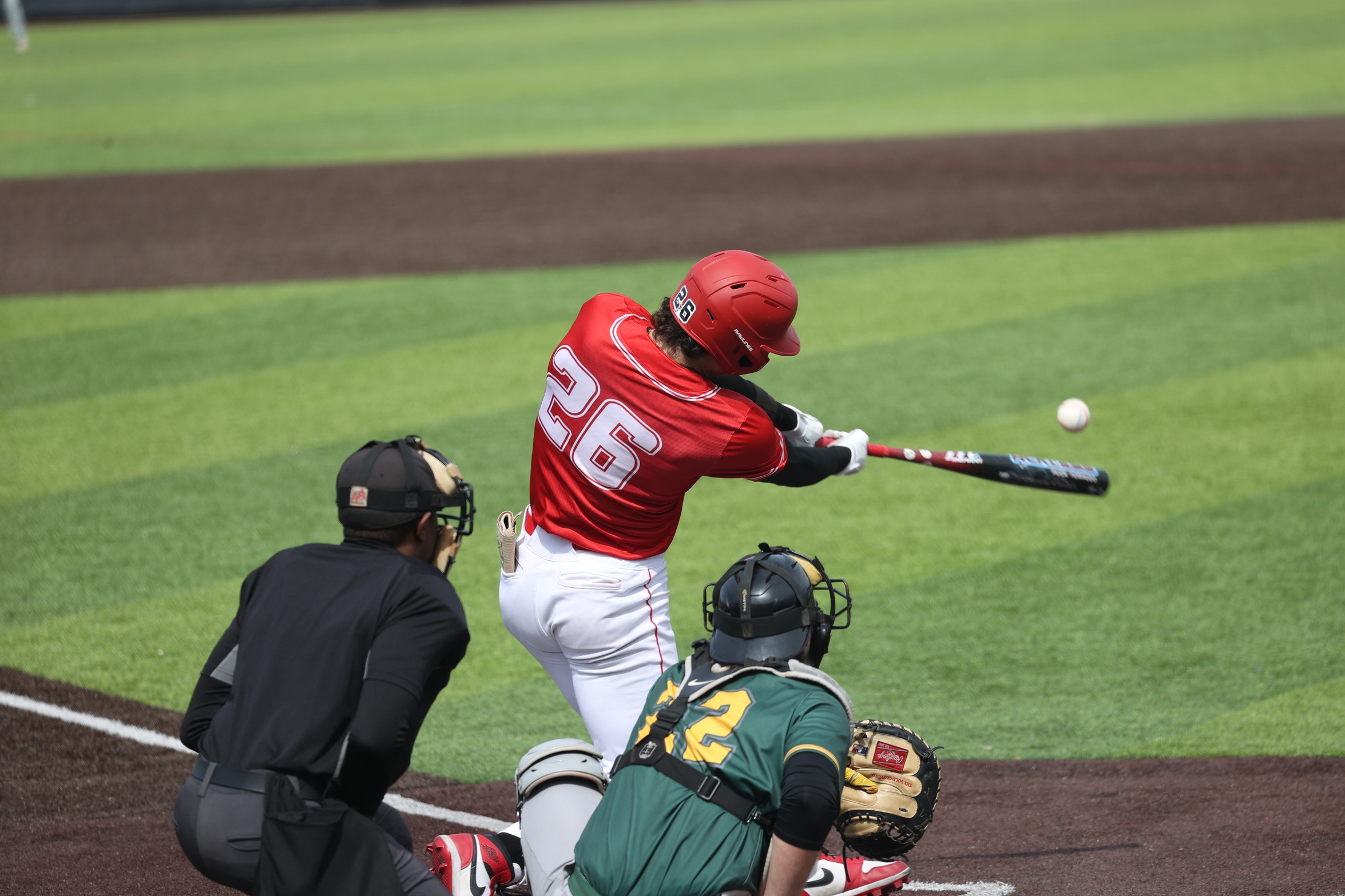 A Cayuga player swings at a pitch.